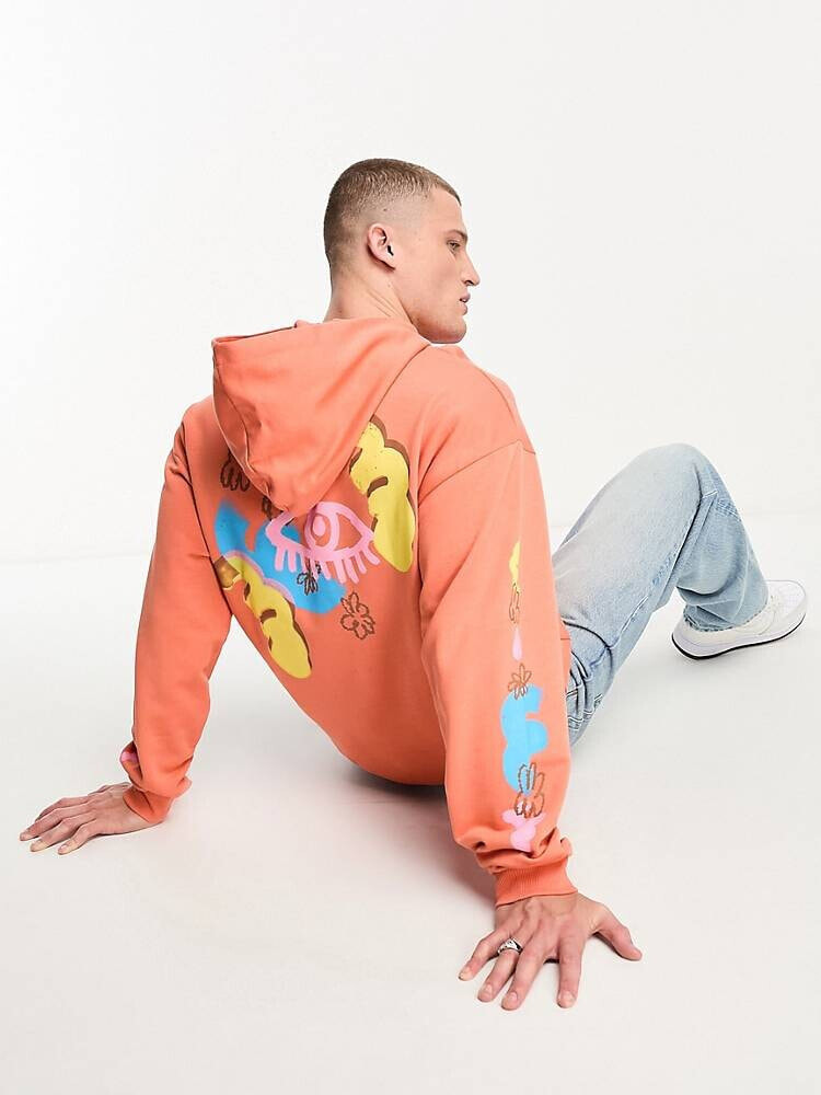 ASOS DESIGN – Oversize-Kapuzenpullover in Orange mit Skater-Prints auf Rücken und Ärmeln