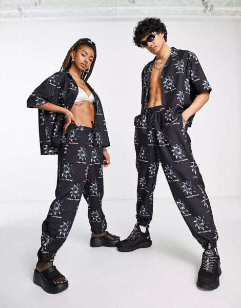 COLLUSION Unisex – Jogginghose in Schwarz mit All-over-Print und Nullerjahre-Schnitt, Kombiteil