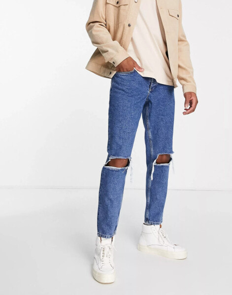 ASOS DESIGN tapered jeans in mid wash blue with knee rips