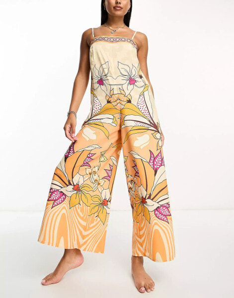 River Island – Strand-Jumpsuit mit tropischem Print in Orange und weitem Bein