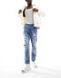 ASOS DESIGN tapered fit jeans with heavy rips in mid wash blue