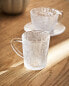 Glass cup with raised design