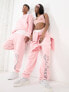 Фото #1 товара ASOS Design unisex co-ord relaxed joggers with prints in pink wash