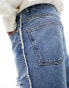 ASOS DESIGN tapered fit jeans with heavy rips in mid wash blue