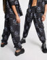 COLLUSION Unisex – Jogginghose in Schwarz mit All-over-Print und Nullerjahre-Schnitt, Kombiteil