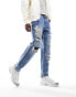 ASOS DESIGN tapered fit jeans with heavy rips in mid wash blue